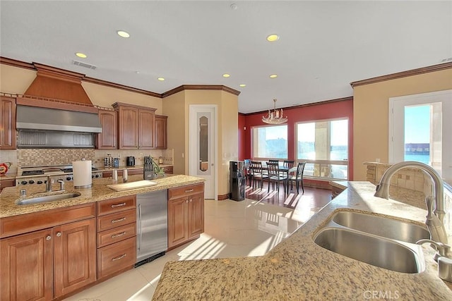 kitchen with decorative backsplash, sink, hanging light fixtures, a water view, and light tile patterned floors