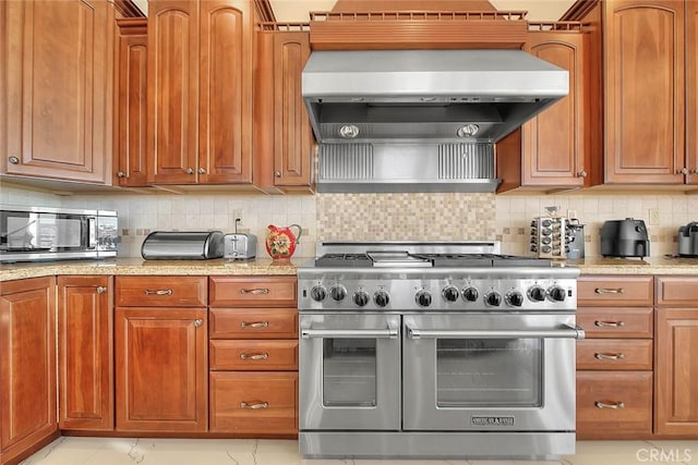 kitchen with light tile patterned floors, stainless steel appliances, wall chimney exhaust hood, and tasteful backsplash