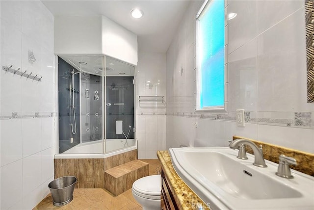 full bathroom with tiled shower / bath combo, tile patterned flooring, vanity, tile walls, and toilet