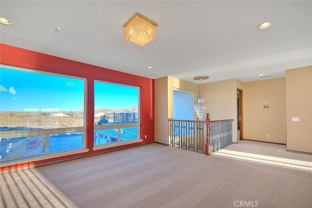 carpeted spare room with a notable chandelier