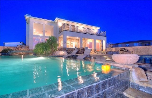 pool at night featuring a grill and a patio