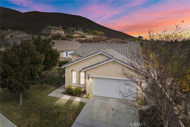 view of front of home with a garage, a mountain view, and a lawn