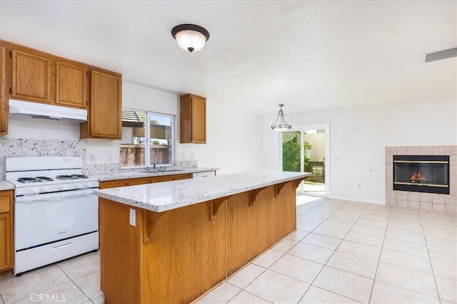 kitchen with decorative light fixtures, light tile patterned flooring, a fireplace, a kitchen island, and white gas range