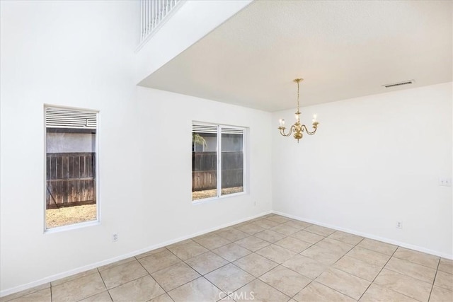 tiled empty room featuring a chandelier