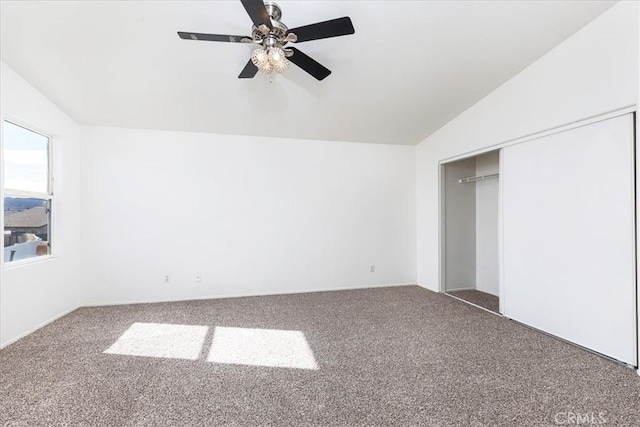 unfurnished bedroom featuring ceiling fan, a closet, carpet floors, and vaulted ceiling