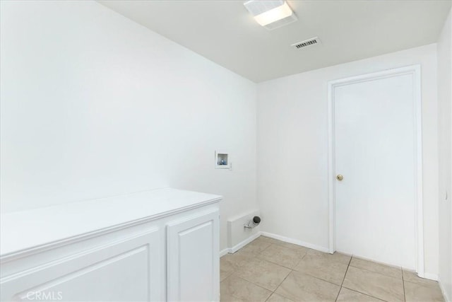 clothes washing area featuring cabinets, washer hookup, and light tile patterned floors