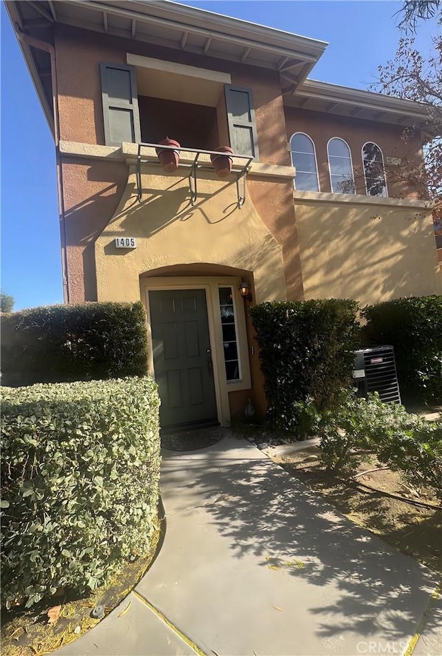 entrance to property featuring central AC and stucco siding