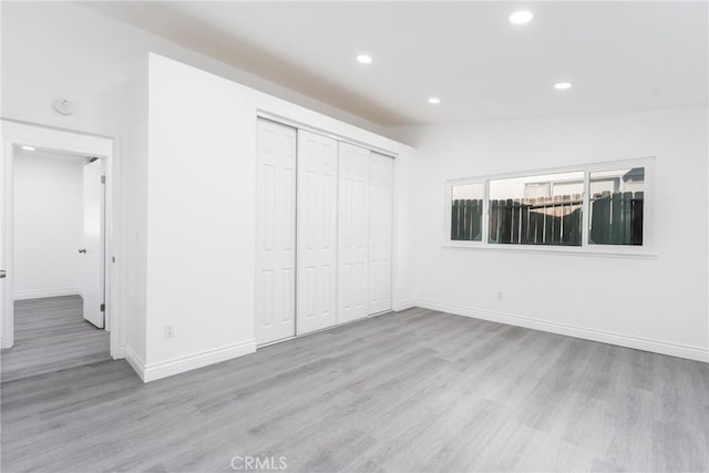 unfurnished bedroom with lofted ceiling, a closet, and light hardwood / wood-style floors