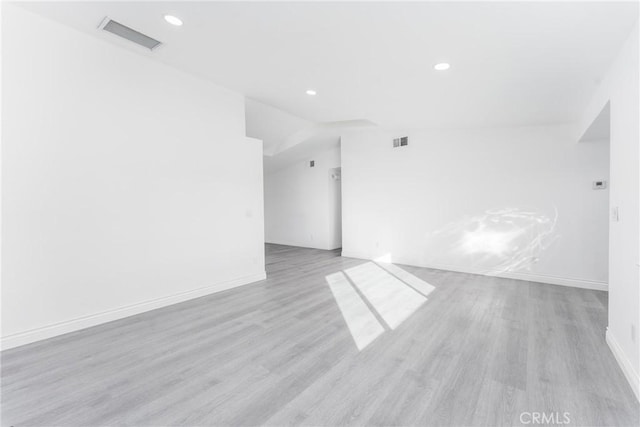 spare room featuring light wood-type flooring and lofted ceiling