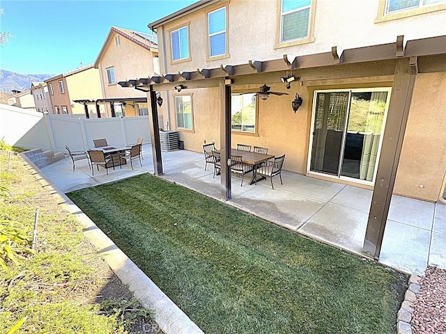 rear view of house featuring ceiling fan, a yard, a mountain view, and a patio area