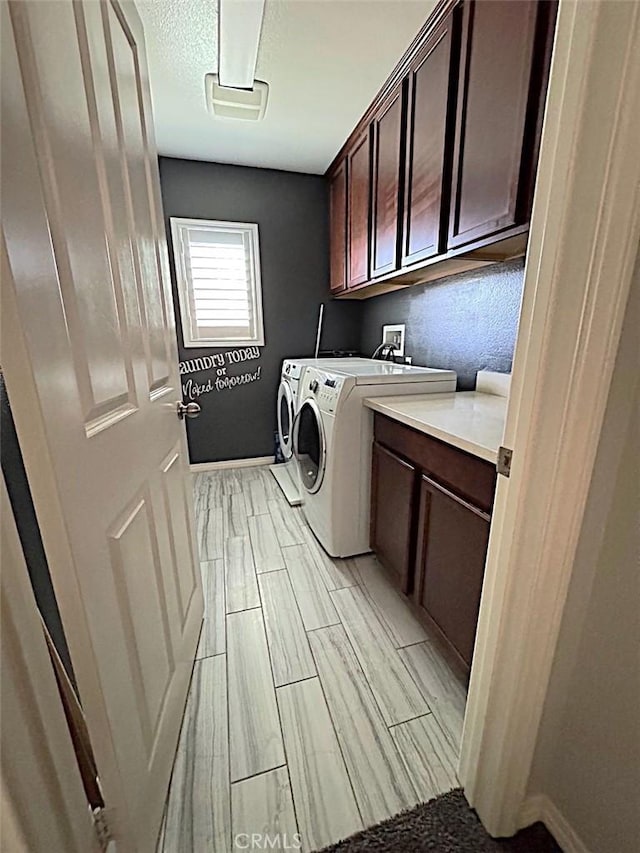 laundry area with cabinets, washer and clothes dryer, and light hardwood / wood-style floors