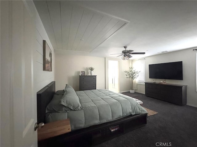 bedroom featuring dark colored carpet, wood ceiling, and ceiling fan