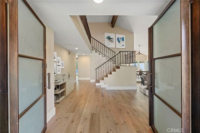 foyer entrance featuring light hardwood / wood-style flooring, lofted ceiling with beams, and a notable chandelier