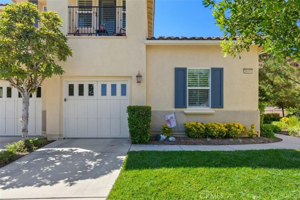 mediterranean / spanish-style home featuring a front lawn, a garage, and a balcony