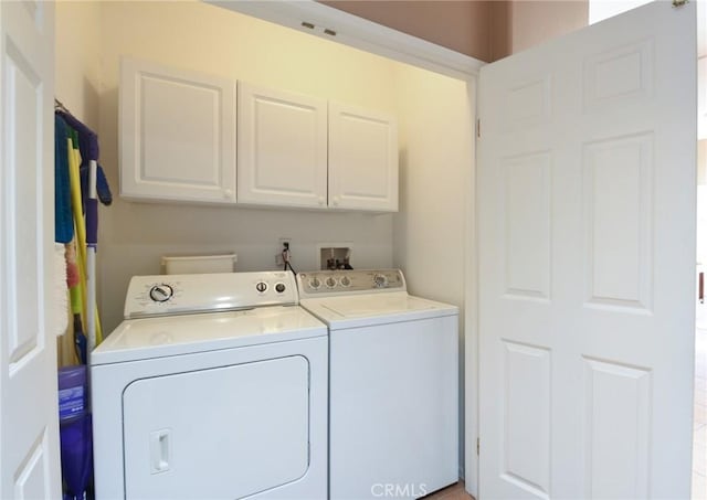 clothes washing area with washing machine and clothes dryer and cabinets