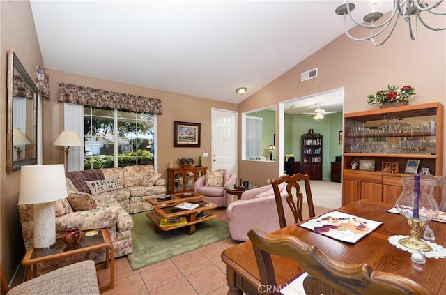 living room featuring ceiling fan with notable chandelier, light tile patterned floors, and lofted ceiling