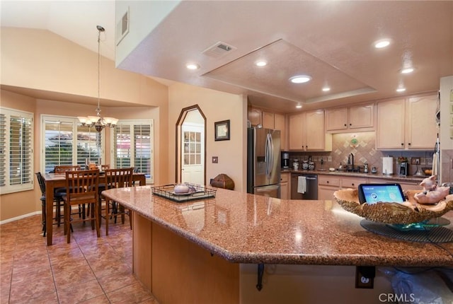 kitchen featuring decorative light fixtures, a notable chandelier, sink, a tray ceiling, and appliances with stainless steel finishes