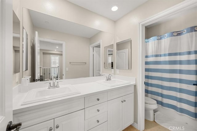 bathroom featuring toilet, vanity, and curtained shower