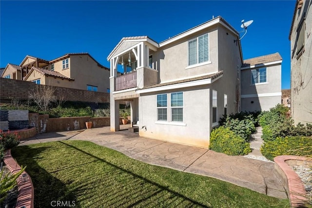 back of house with a yard, a patio area, and a balcony