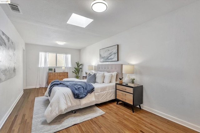 bedroom featuring wood-type flooring and a skylight