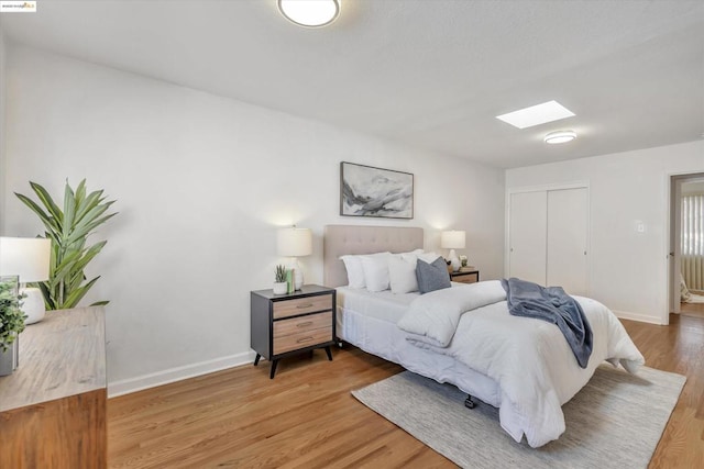 bedroom featuring hardwood / wood-style flooring, a closet, and a skylight