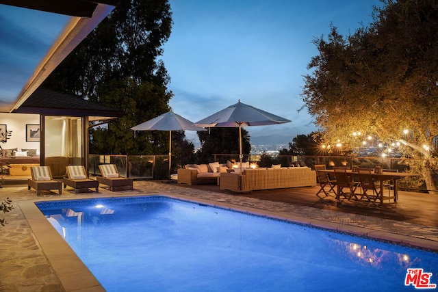 pool at dusk with an outdoor hangout area