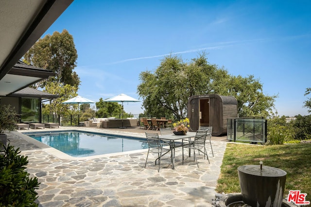 view of pool with a patio area, outdoor lounge area, and a storage shed