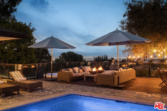 pool at dusk with a wooden deck and outdoor lounge area