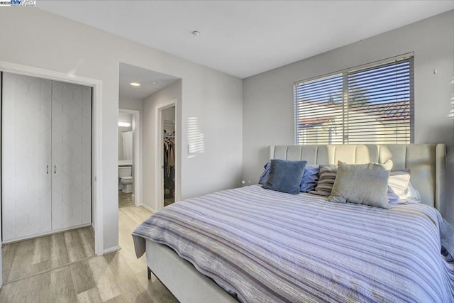 bedroom featuring ensuite bathroom, a walk in closet, light hardwood / wood-style flooring, and a closet