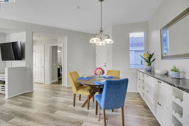 dining area with light wood-type flooring and a chandelier