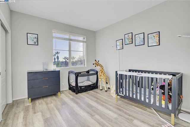 bedroom with a crib and light hardwood / wood-style floors