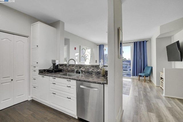 kitchen featuring dark wood-type flooring, dark stone countertops, stainless steel dishwasher, white cabinets, and sink