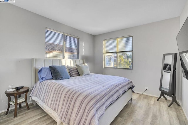 bedroom with light wood-type flooring and multiple windows