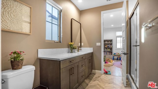 bathroom with toilet, a shower with door, vanity, and parquet flooring