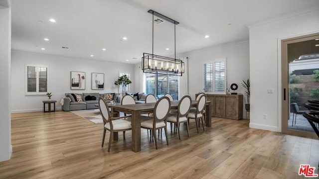 dining space with crown molding, a notable chandelier, and light wood-type flooring