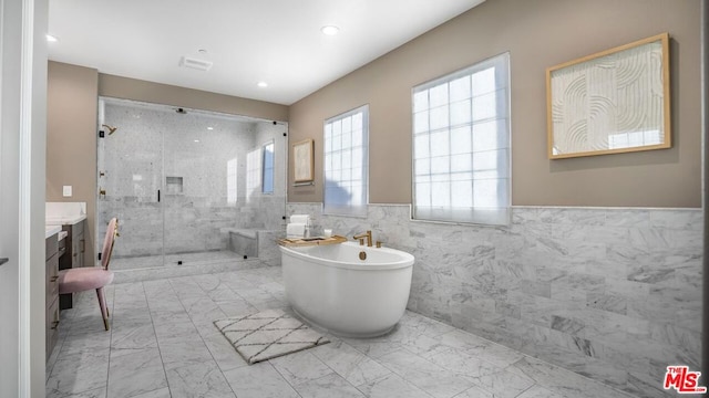 bathroom with tile walls, separate shower and tub, and vanity