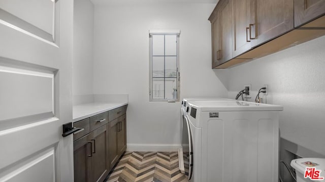 clothes washing area featuring cabinets and washer and dryer