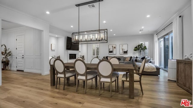 dining space featuring light hardwood / wood-style flooring and crown molding