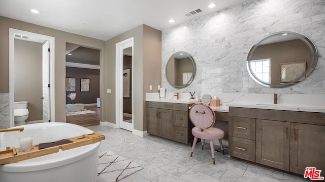 bathroom featuring toilet, vanity, and a bathtub