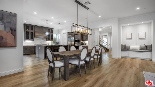 dining room featuring an inviting chandelier, ornamental molding, light hardwood / wood-style flooring, and sink