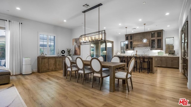 dining area featuring ornamental molding and light hardwood / wood-style flooring