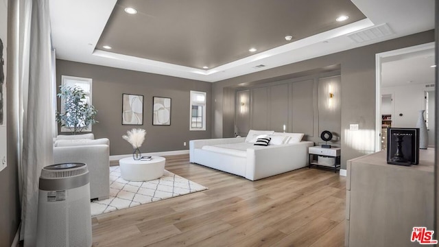 bedroom with a tray ceiling and light hardwood / wood-style floors