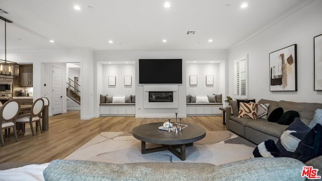 living room featuring crown molding and light hardwood / wood-style flooring