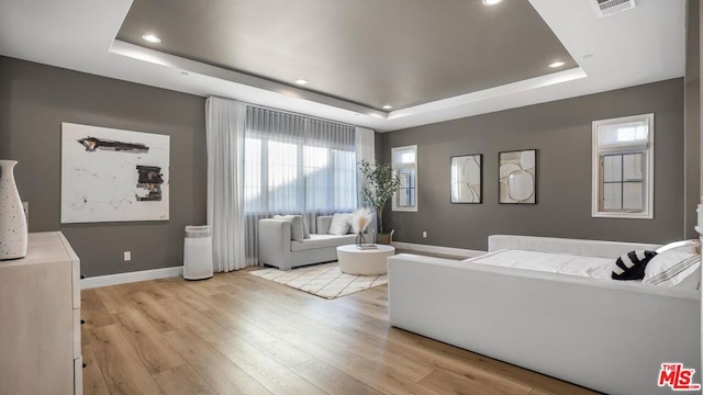 living room featuring light hardwood / wood-style floors and a tray ceiling