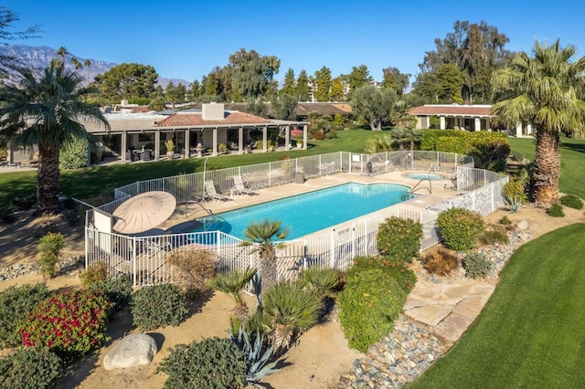 view of pool featuring a patio area, a mountain view, and a yard