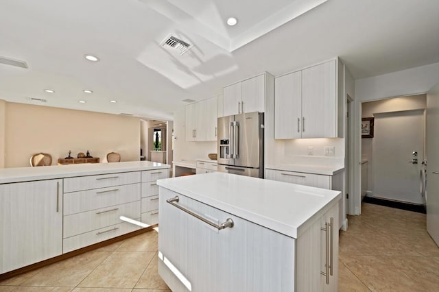 kitchen featuring light tile patterned flooring, white cabinets, high end refrigerator, and a center island