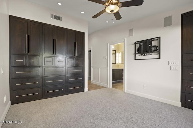 unfurnished bedroom with ensuite bath, light colored carpet, and ceiling fan