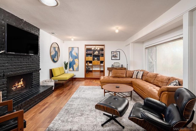 living room with a textured ceiling, light wood-type flooring, and a fireplace