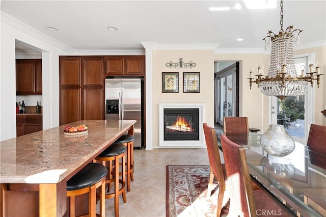 kitchen featuring a kitchen island, light tile patterned floors, light stone counters, stainless steel fridge with ice dispenser, and crown molding