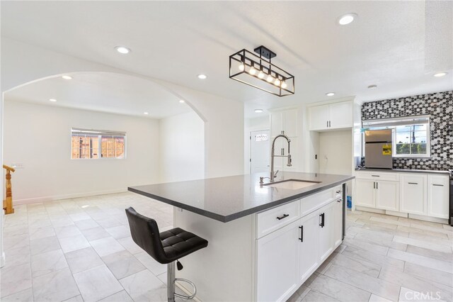 kitchen with a kitchen island with sink, refrigerator, sink, and white cabinetry